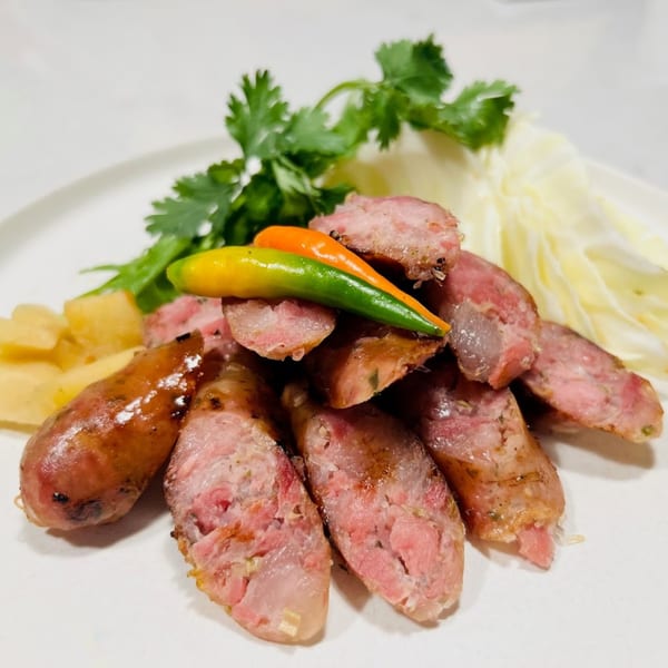 Grilled Thai sausages, sliced and served with fresh cilantro, cabbage, ginger, and chili peppers.