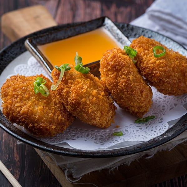 Four crispy Thai fried shrimp cakes with green onions and a sweet chili dipping sauce.
